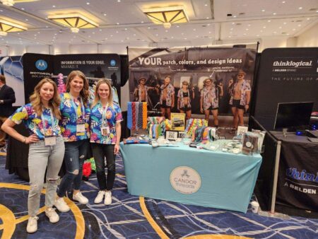 A photo of Sandra, Becky and Katie all standing together to the left of our Sea Air Space booth.
